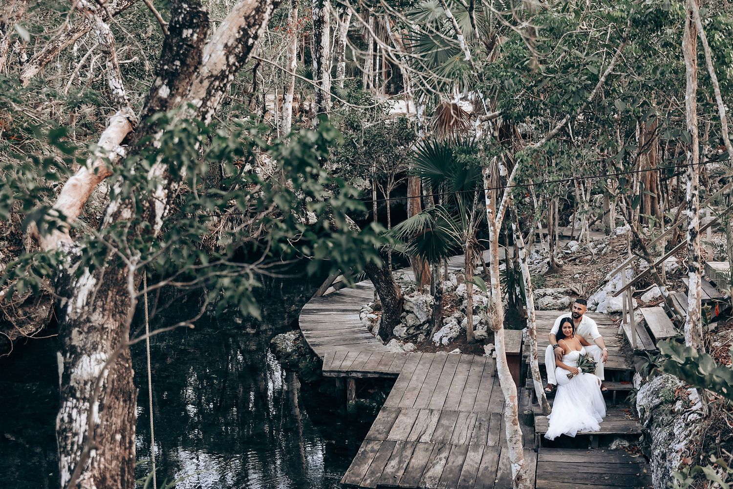 Wedding ceremony setup on wooden platform surrounded by tall trees in natural setting.