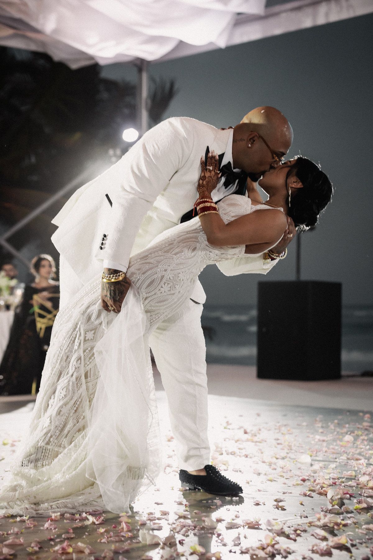 Couple sharing romantic dip kiss on dance floor at elegant outdoor nighttime wedding reception.