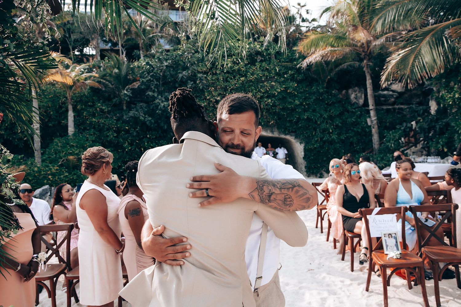 Wedding guests seated in white chairs during outdoor beach ceremony.