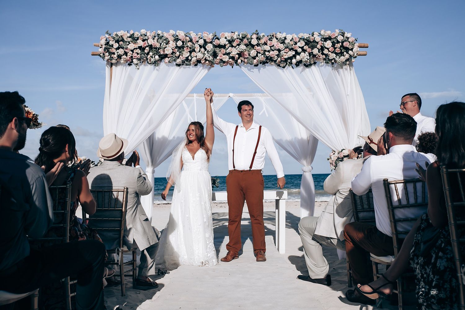 Elegant beach wedding ceremony setup with white canopy and chairs overlooking the ocean.