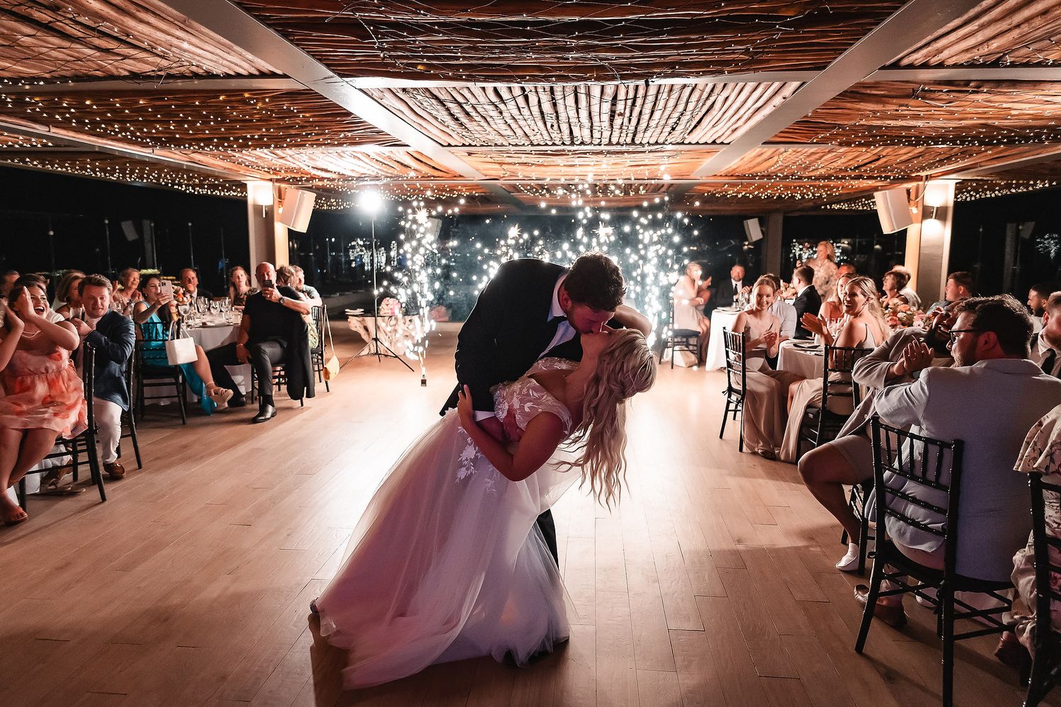 Wedding reception hall with romantic lighting and rustic wooden details.