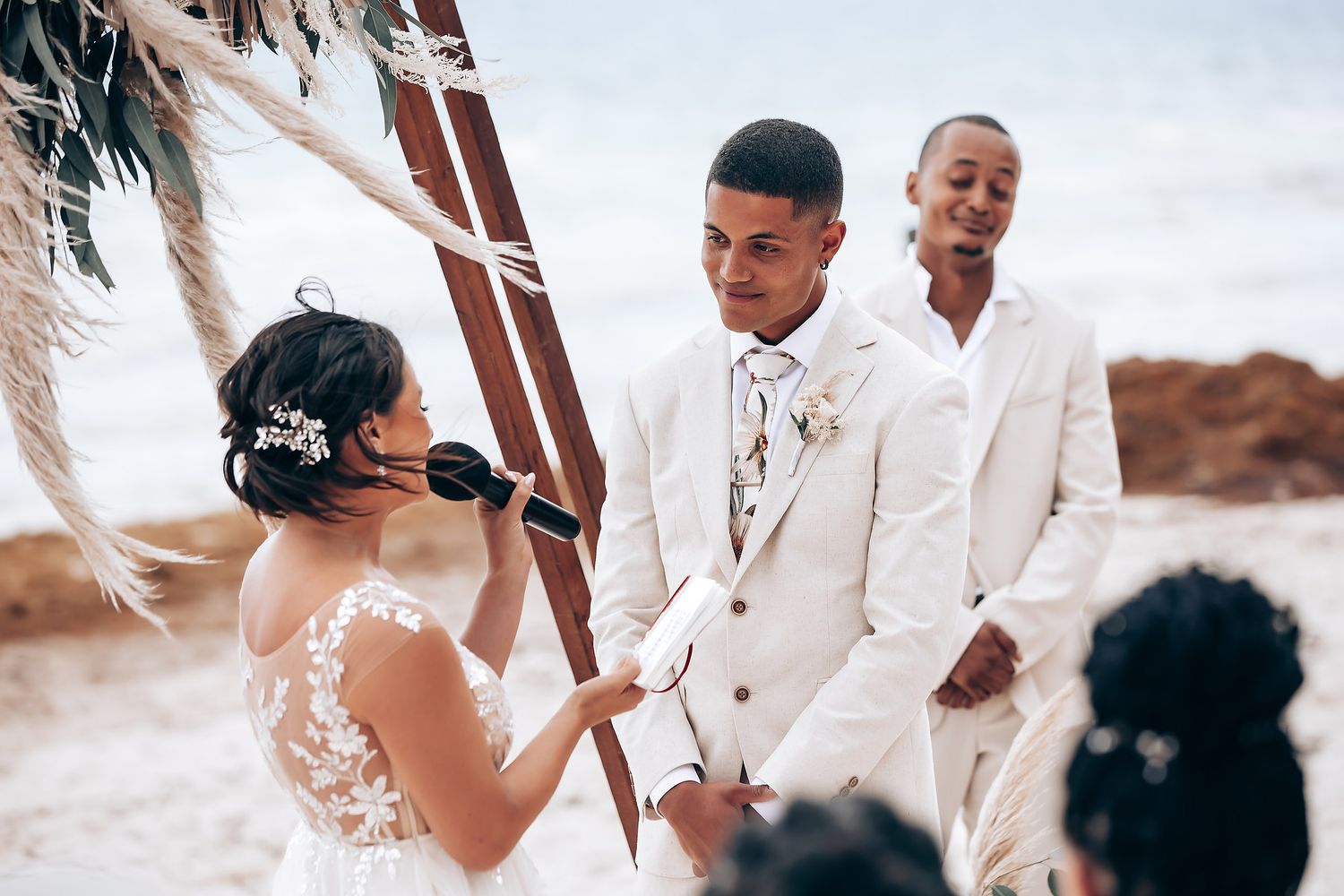 Joyful wedding celebration on a tropical beach with guests in formal attire.