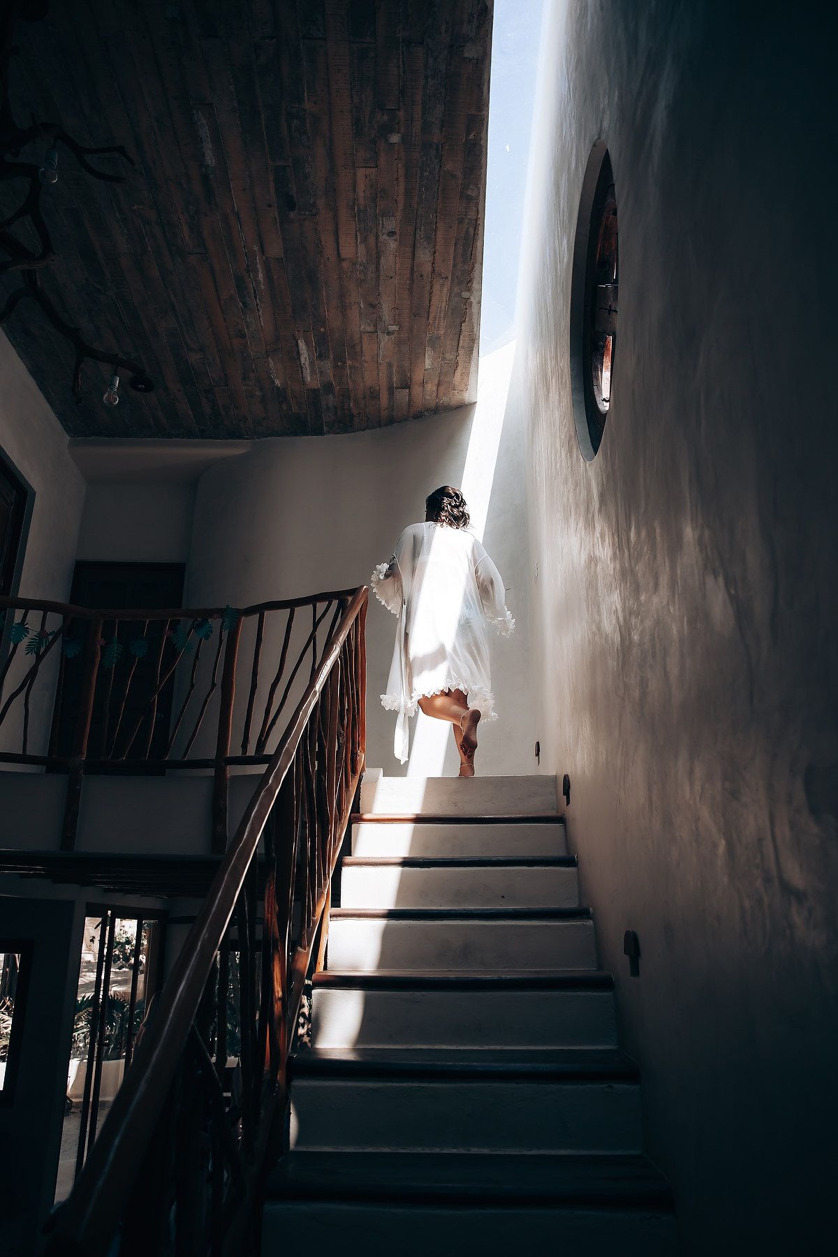 Dark staircase with dramatic shadows and light streaming through windows in an old building interior.