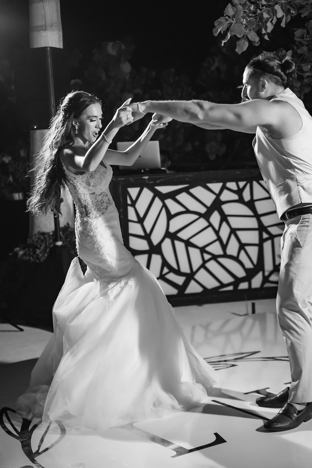 Black and white photo of bride and groom performing energetic first dance at wedding reception.