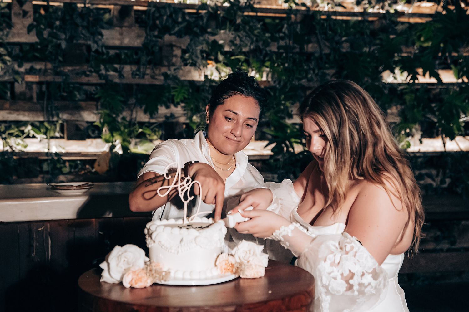 Wedding celebration scene with cake and laughter at a rustic outdoor venue.