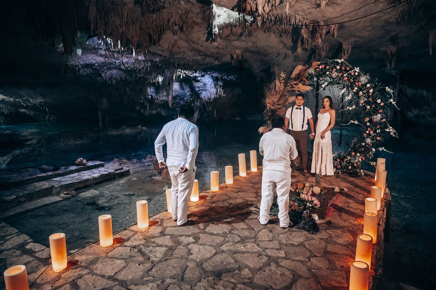 People in white clothing walk along an illuminated stone path with glowing paper lanterns at dusk.