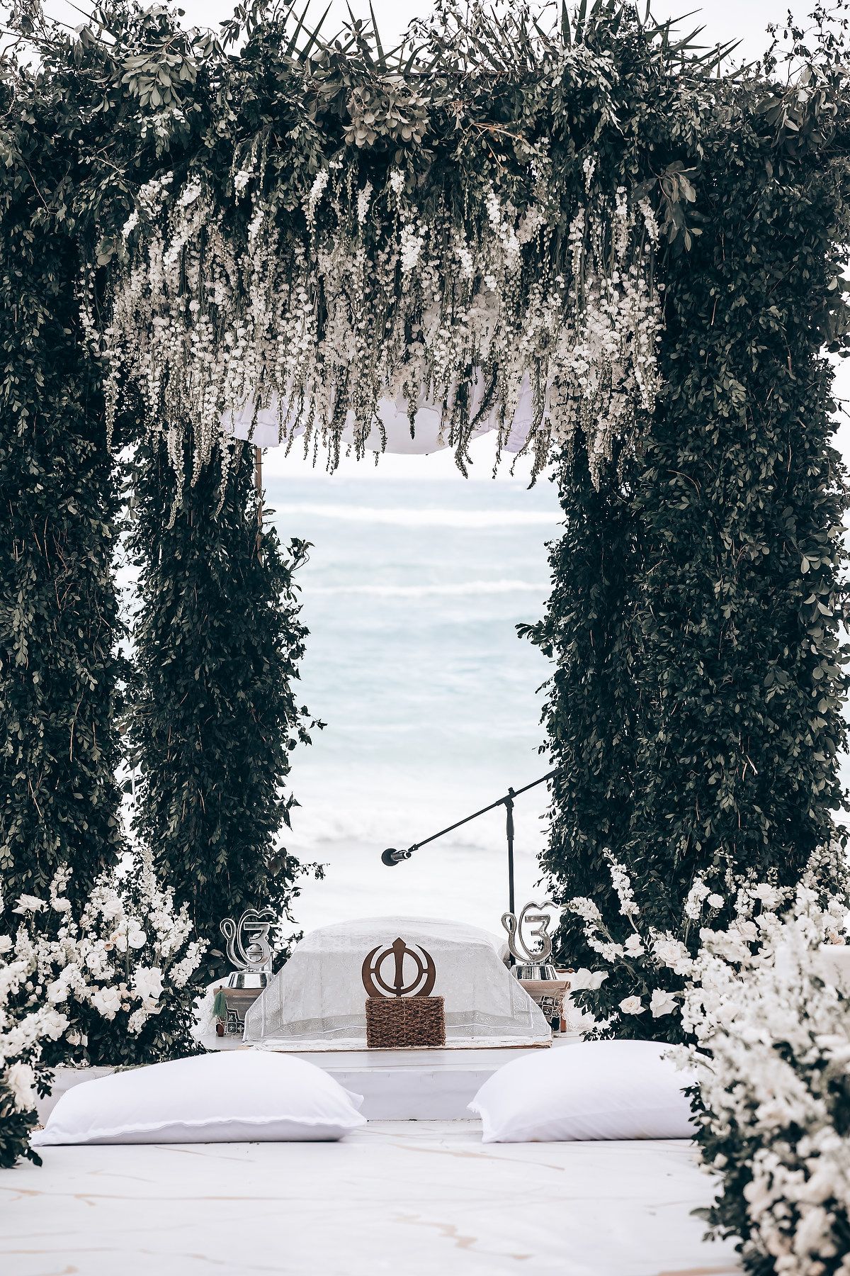 Elegant wedding decor with white floral arrangements and hanging greenery creating a romantic outdoor ceremony space.