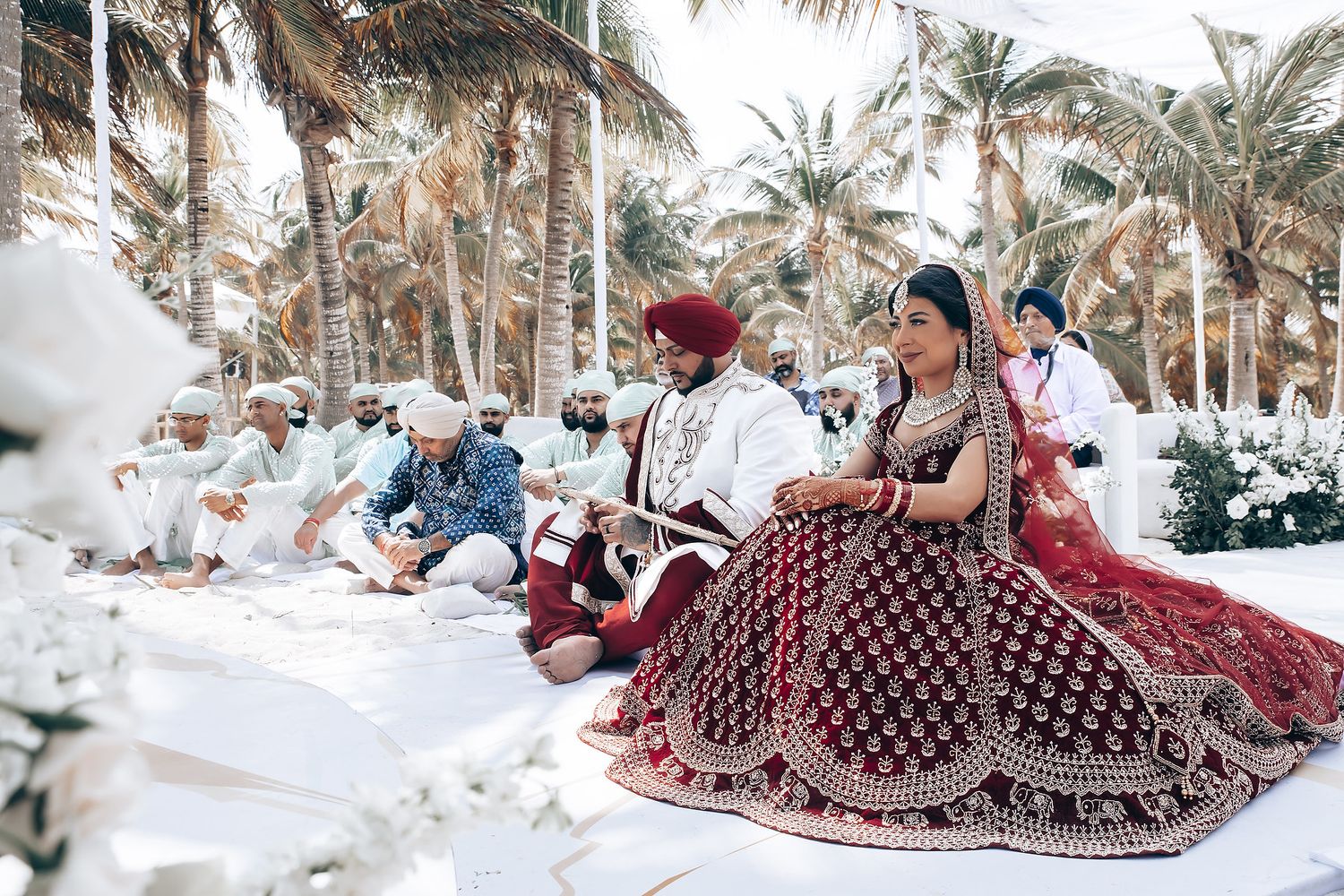 Scenic beach wedding venue with tropical landscaping and white guest seating.