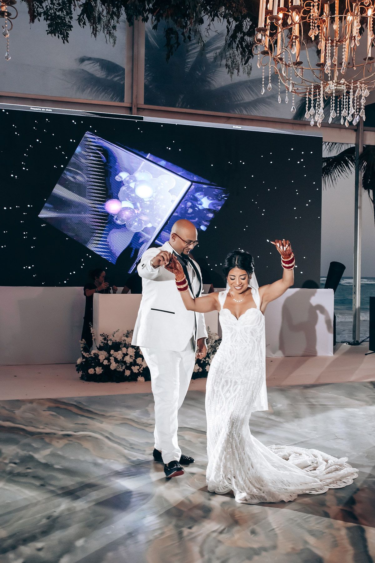 Festive dance celebration with LED screen backdrop and crystal chandeliers overhead.