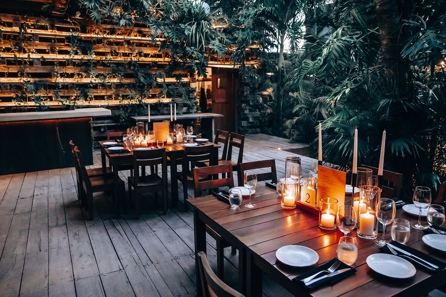 Intimate reception dining setup with glowing candles and rustic wooden tables.