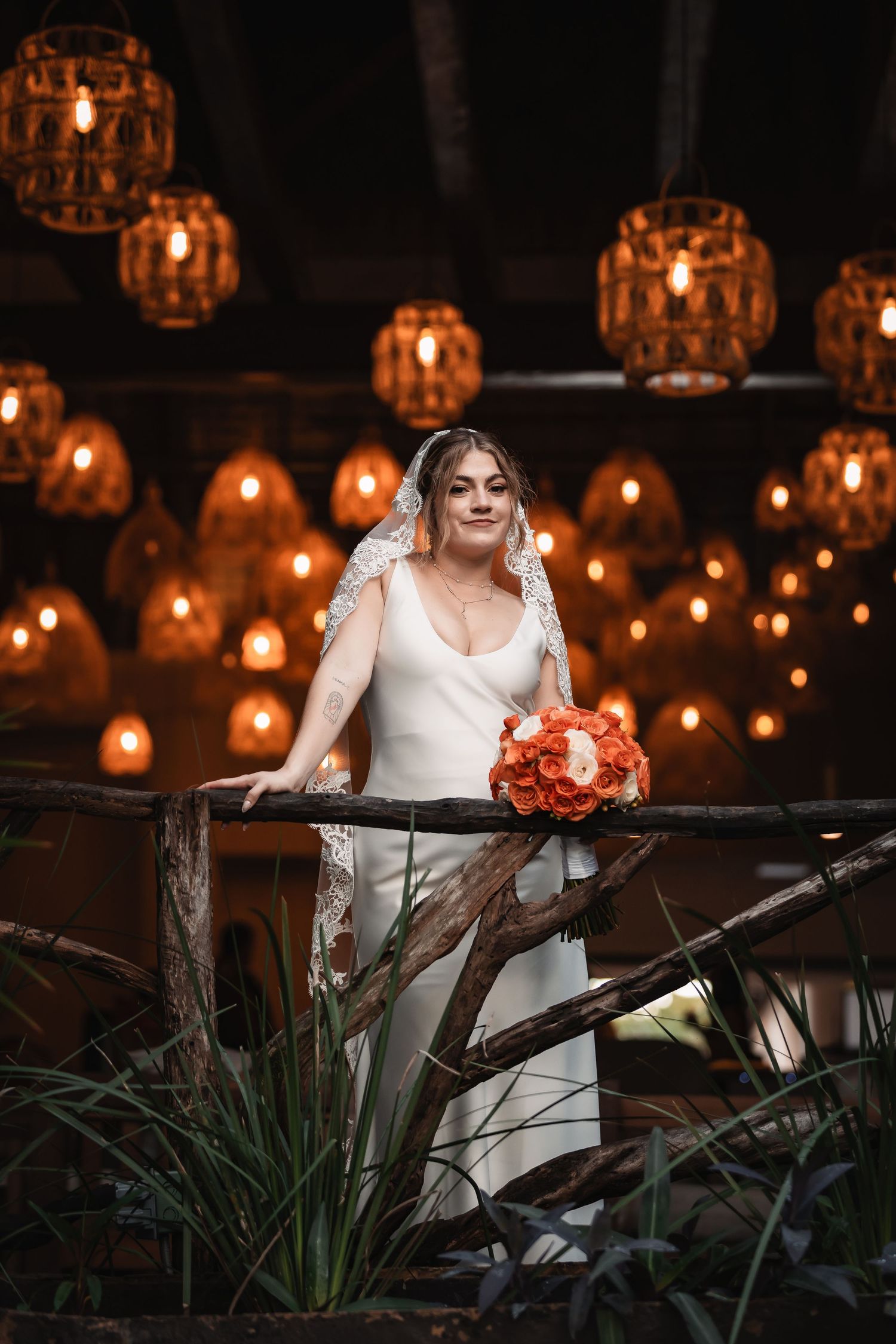Romantic evening wedding scene with glowing lanterns and greenery creating ambient lighting.