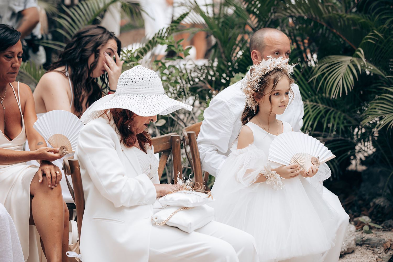 A group of people in white dresses gather together in a lush garden setting for a special occasion.