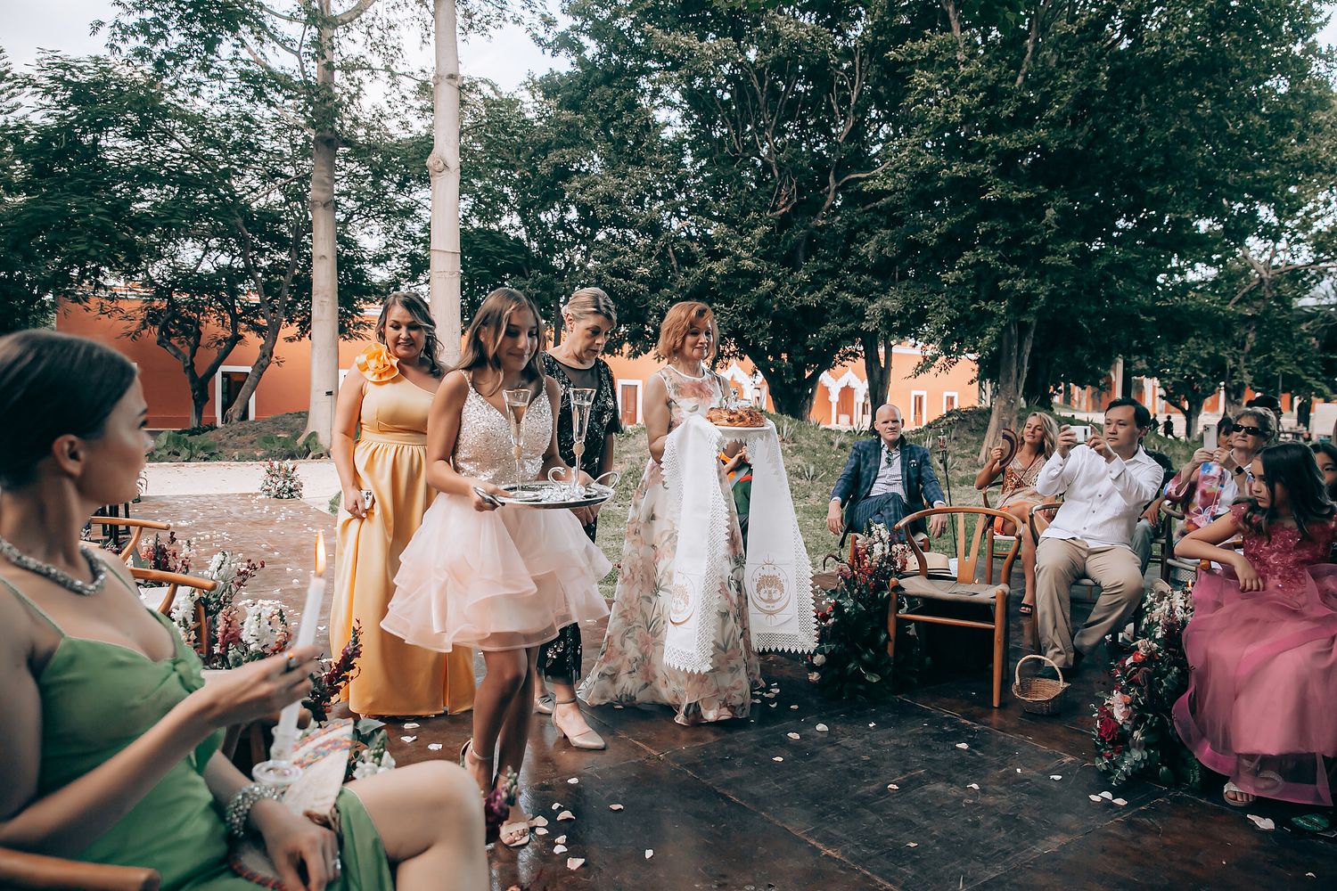 A panoramic collage of an outdoor wedding celebration with guests mingling under trees at dusk.