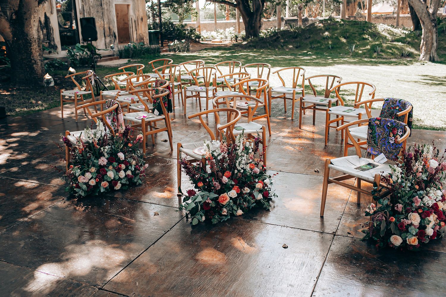 Elegant outdoor wedding reception setup with wooden chairs and floral arrangements on a covered patio.