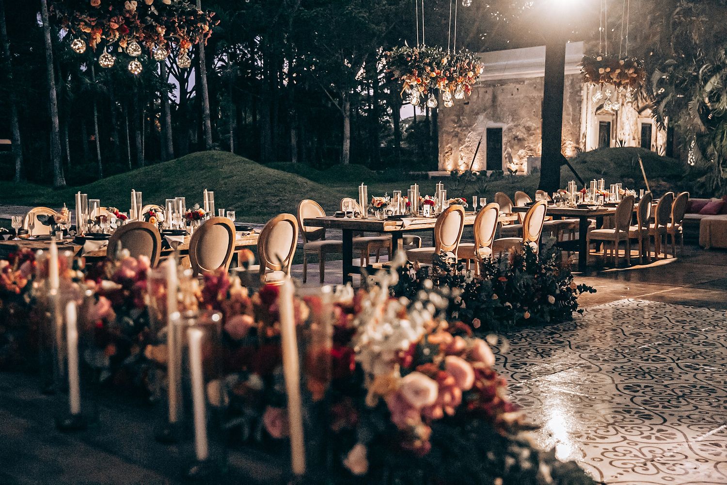 A romantic outdoor wedding venue with string lights and floral decorations illuminated at dusk.