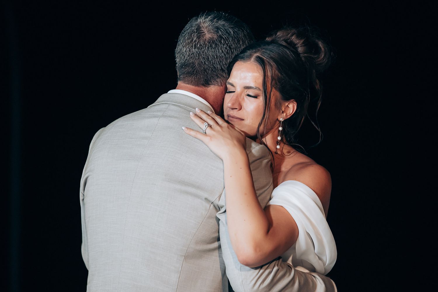 Newlyweds embrace tenderly during their first dance at an evening wedding celebration.