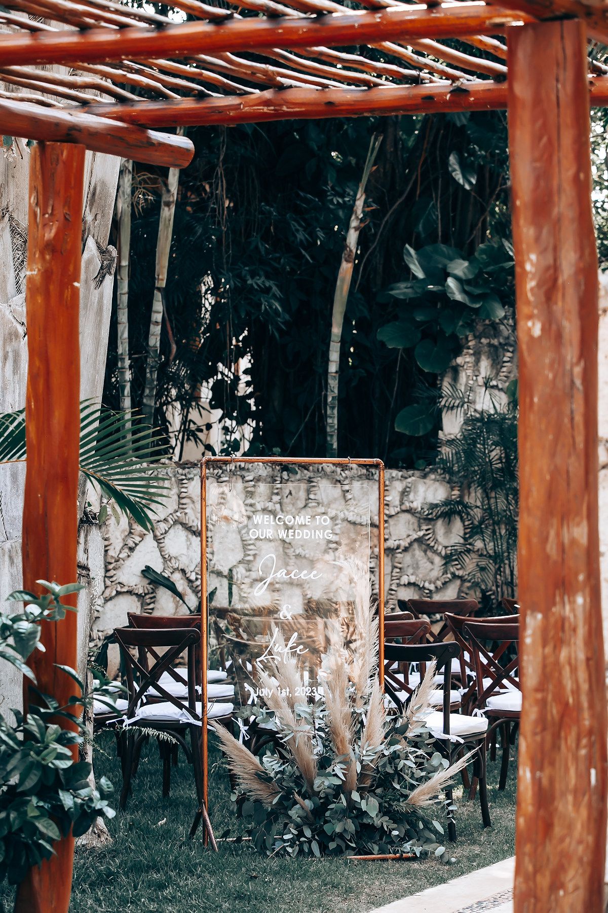 Rustic wooden pergola with tropical garden backdrop and vintage distressed wall creating an intimate seating area.