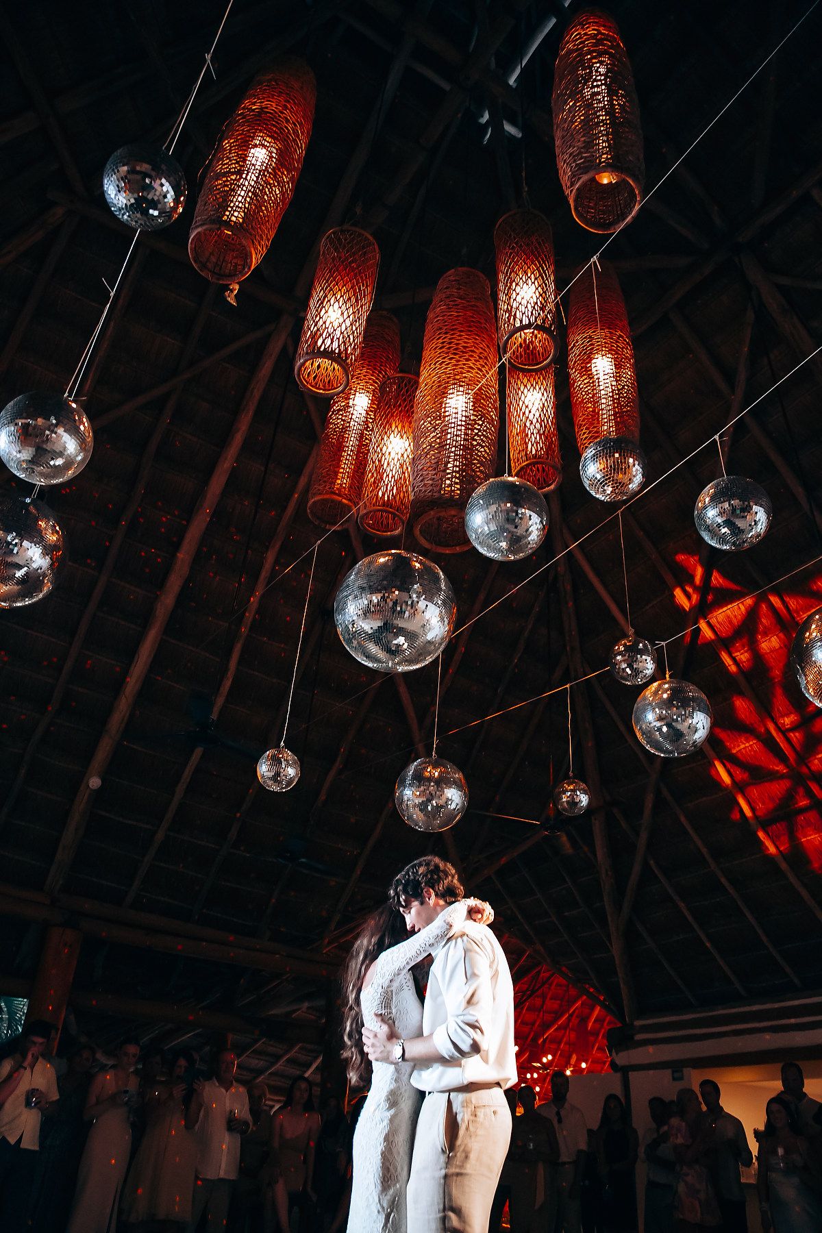 Glass orb lights and red lanterns hang from a rustic wooden ceiling creating a romantic ambiance.