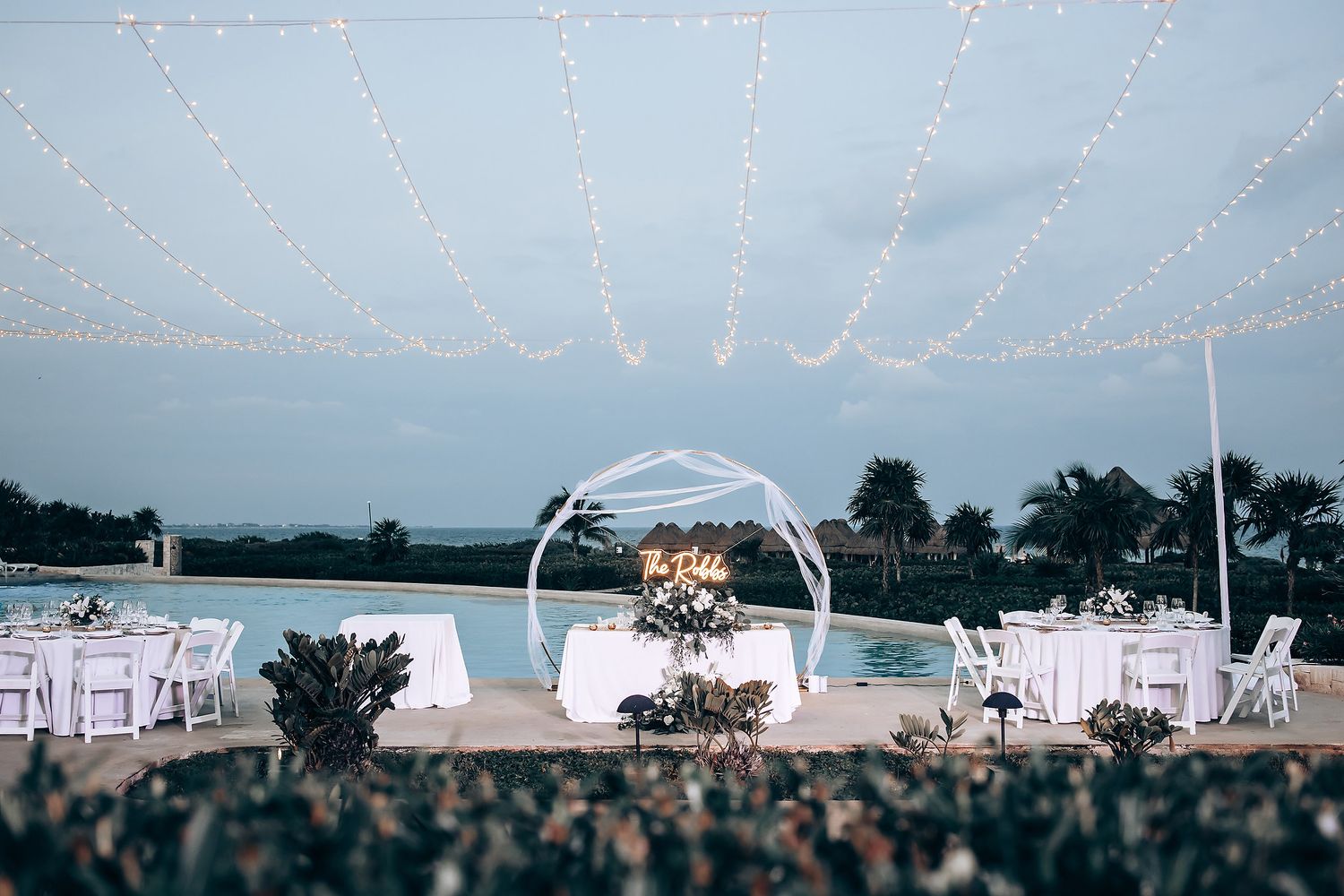 Wedding reception venue decorated with twinkling string lights at dusk.