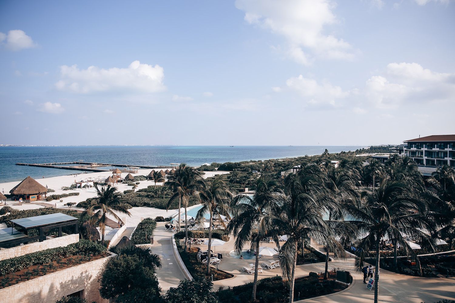 Panoramic view of a beachfront wedding venue with palm trees and ocean views in the background.