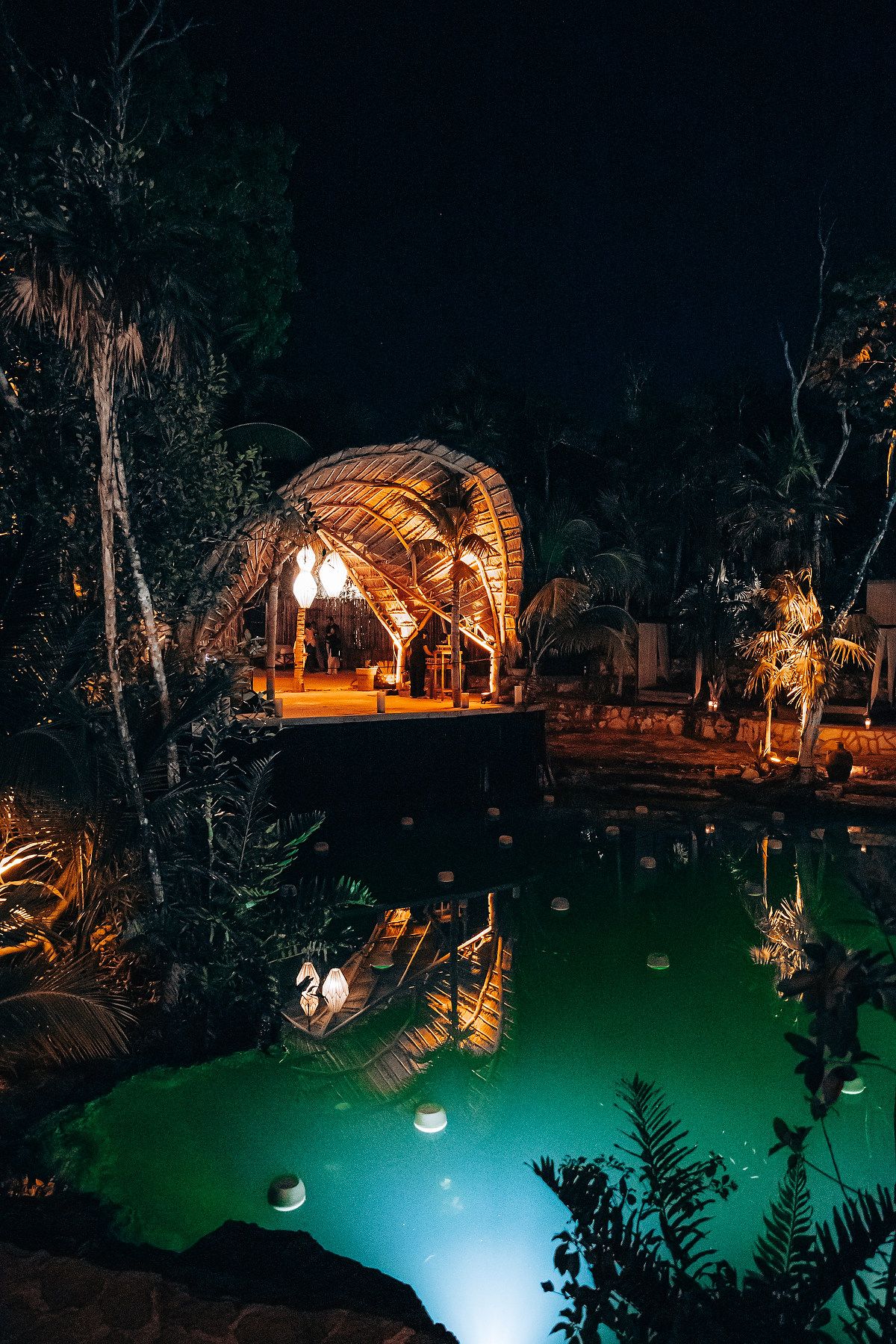 Nighttime outdoor venue with illuminated structures and glowing turquoise pool.