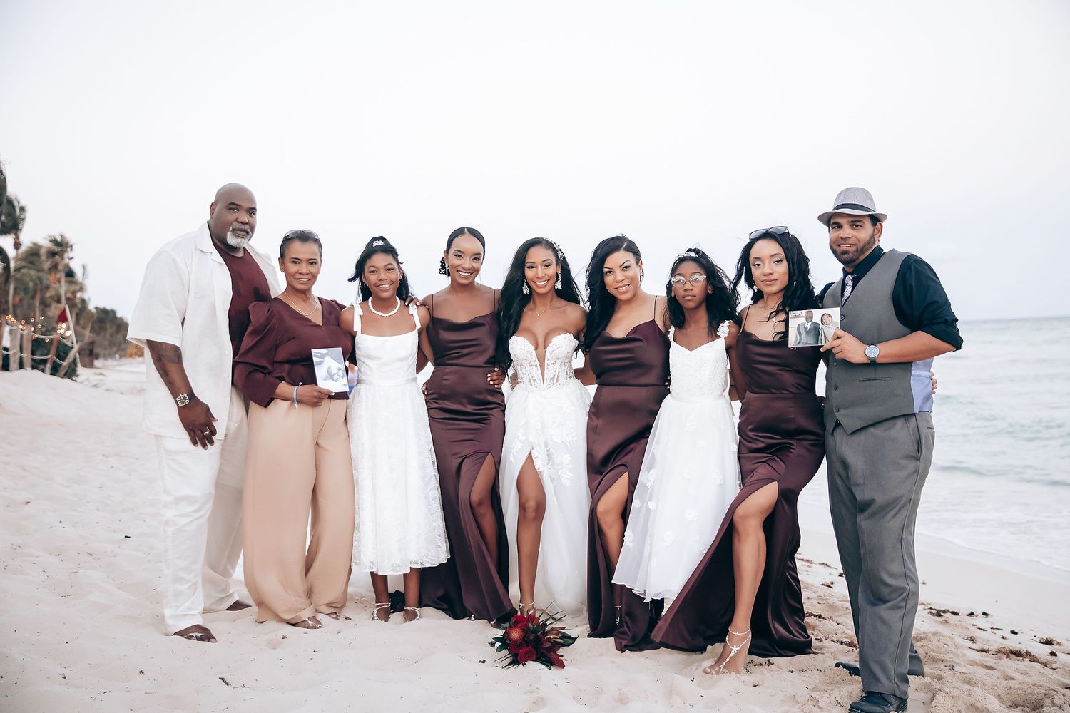 Wedding party poses together on a beach in brown and neutral colored attire.