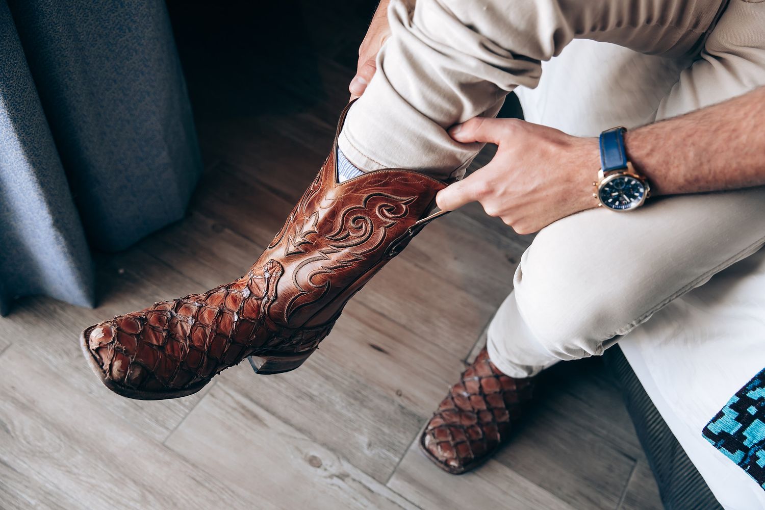 Close-up of brown leather cowboy boots being put on during a wedding preparation.