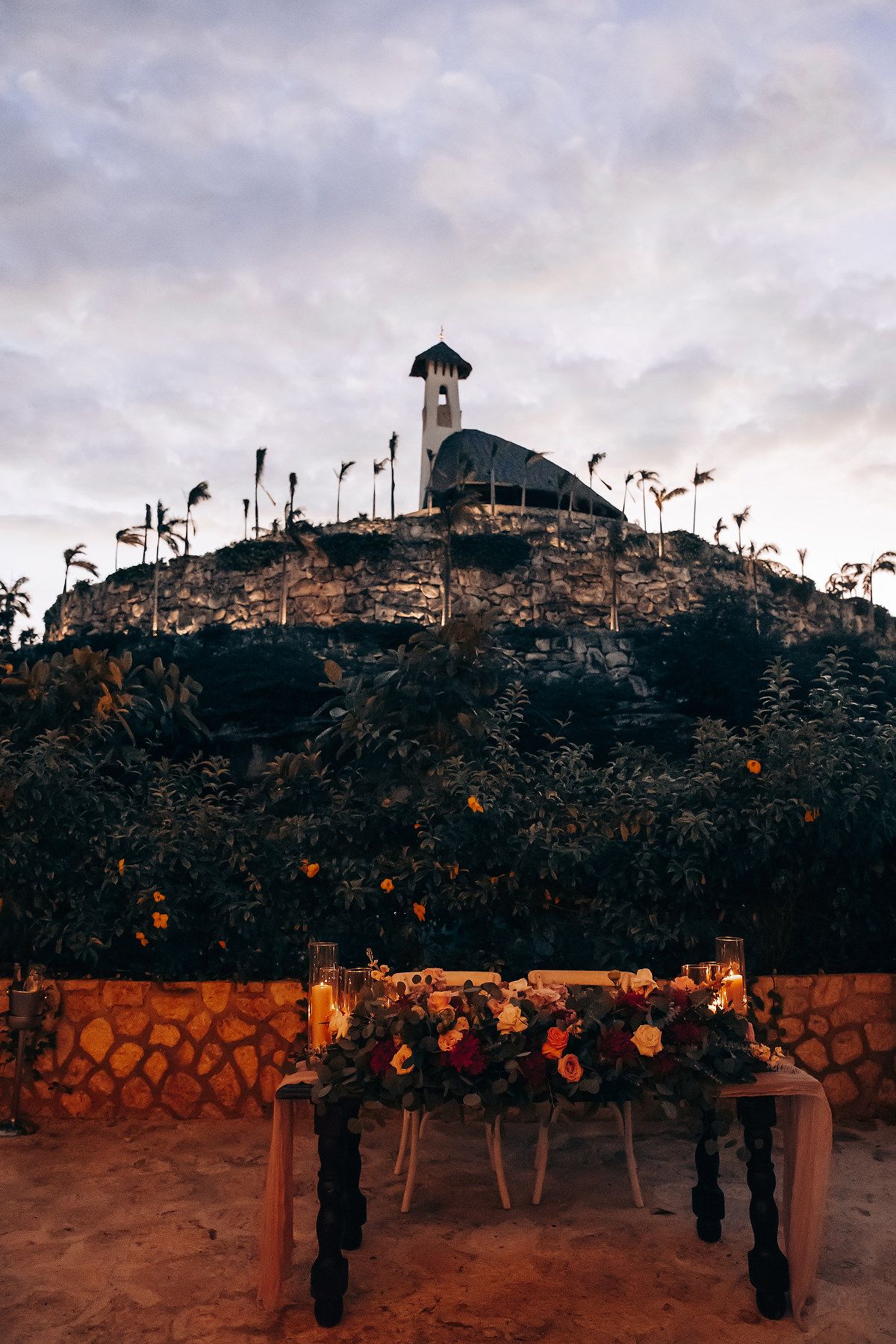 Stone wall garden illuminated with string lights at dusk creating a romantic outdoor ambiance.