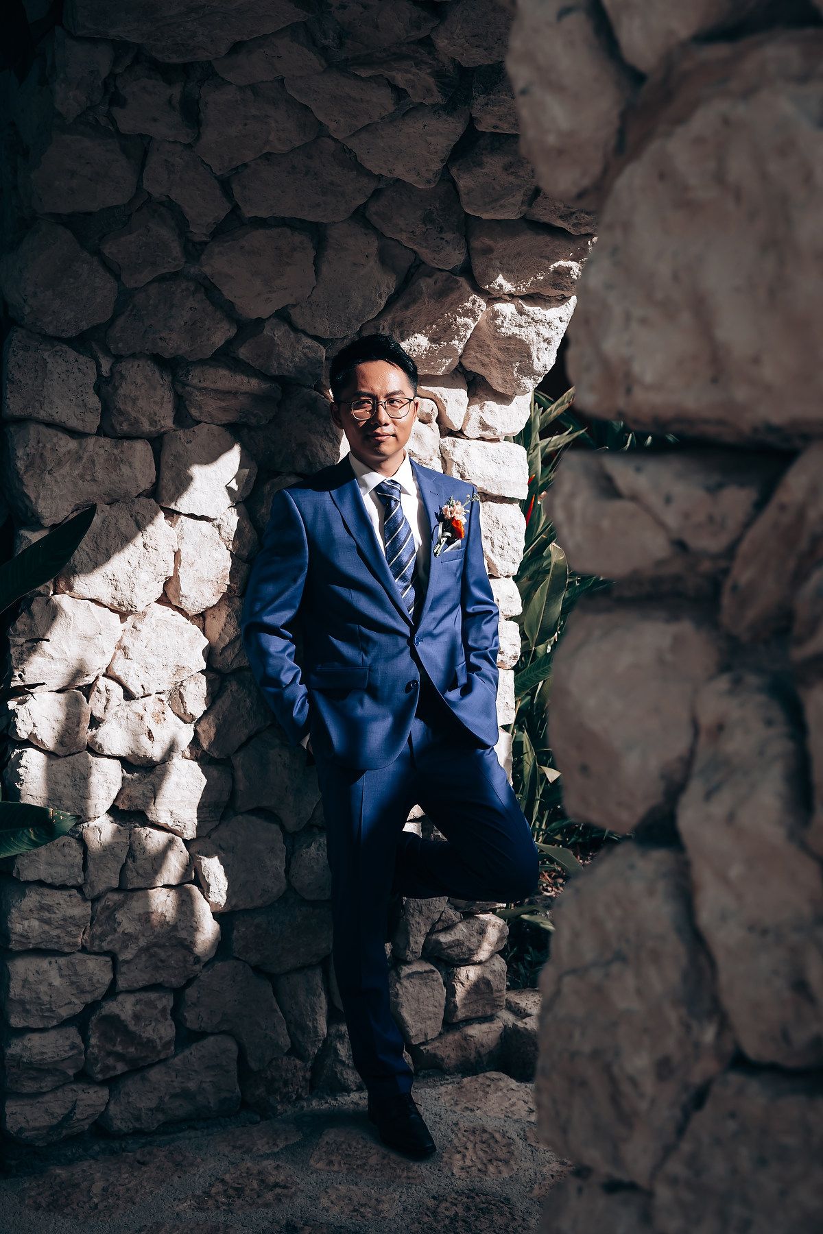 Professional portrait session against a textured stone wall backdrop featuring a blue suit.