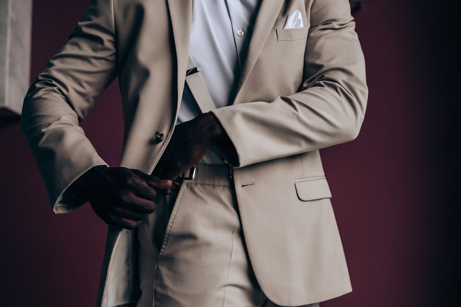 Person wearing a beige suit jacket poses against dark background in professional fashion photography series.