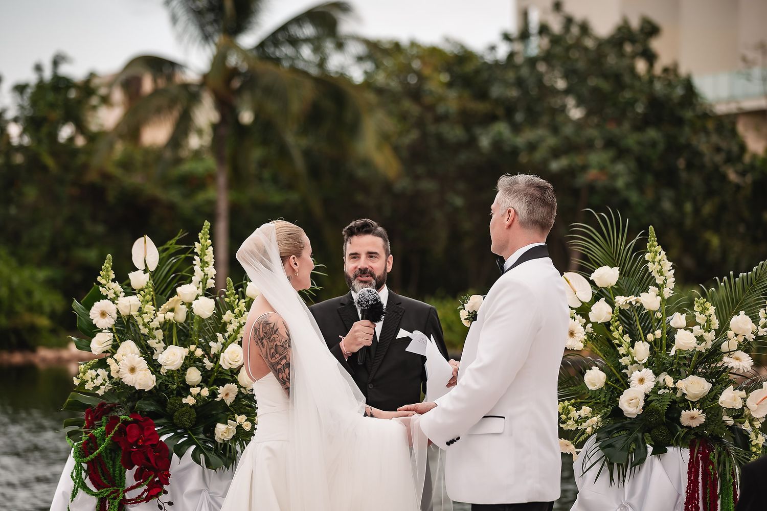 Tropical wedding ceremony with lush floral arrangements and palm trees in the background.