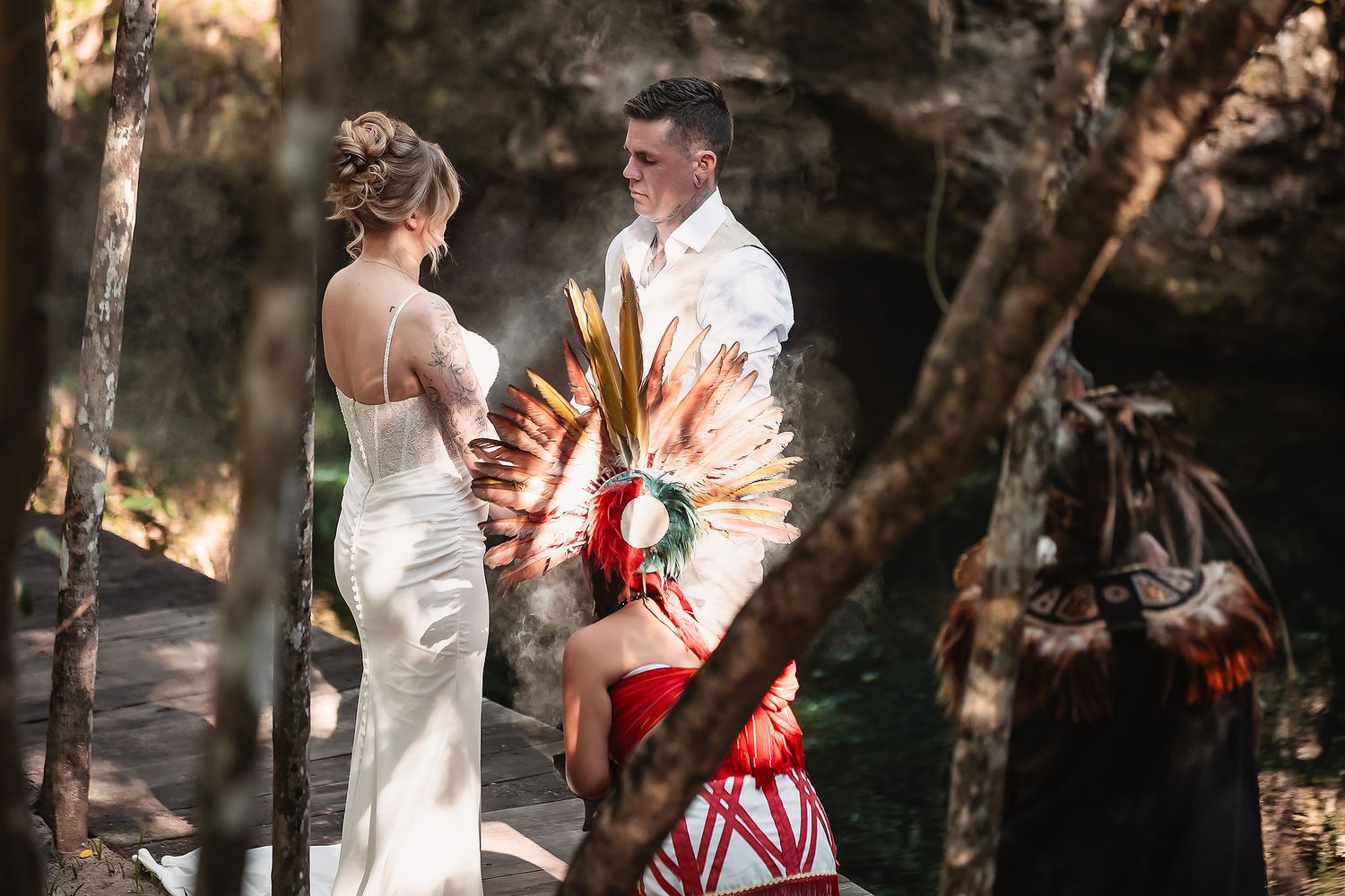 Couple exchanges wedding vows outdoors with a colorful officiant in traditional attire at a scenic forest ceremony.