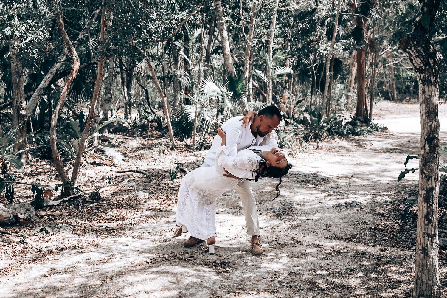 Wedding celebration in a sunlit forest clearing with guests and natural scenery.
