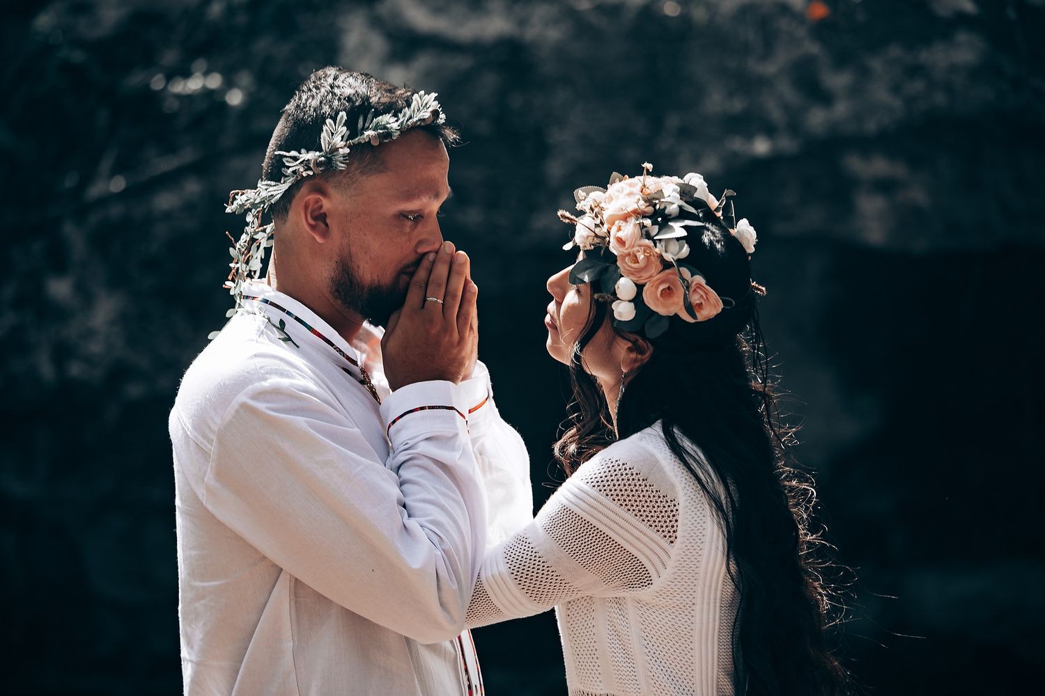 Romantic couple in white clothing embracing in a natural woodland setting.