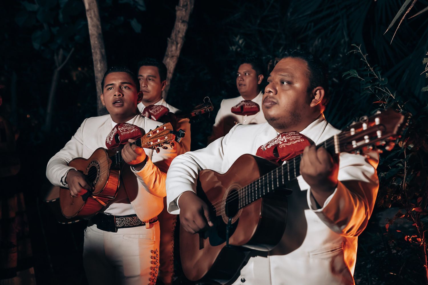 Musicians performing with acoustic guitars at an evening outdoor event.