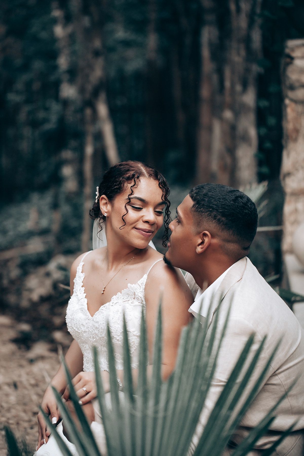 Intimate wedding portraits with a palm frond in the foreground creating natural framing.