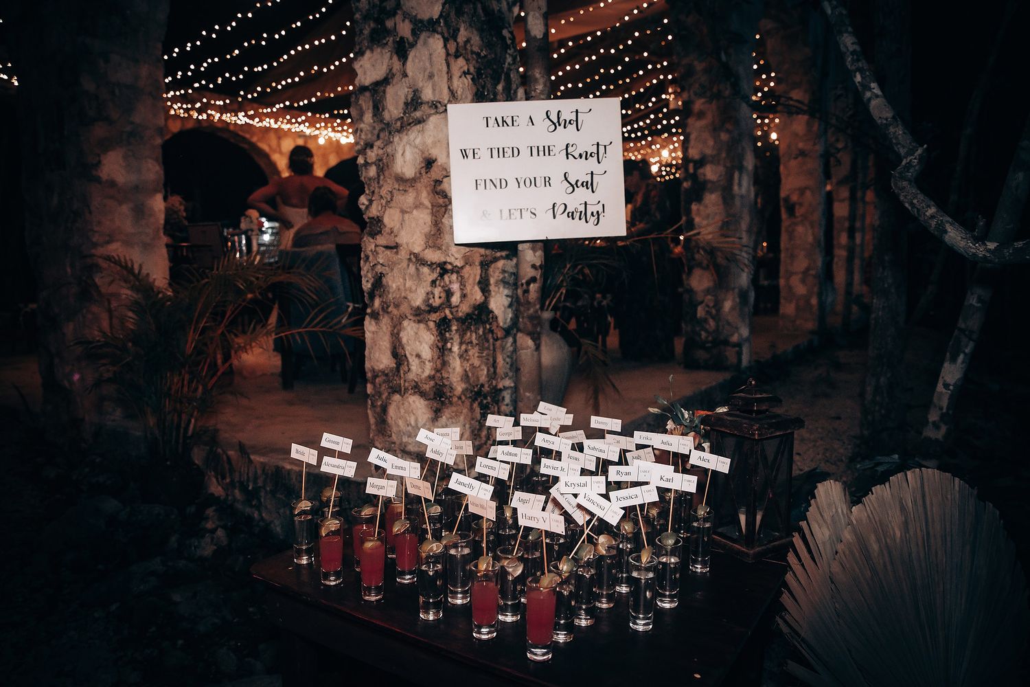 Wedding reception venue with hanging lights and place card display.