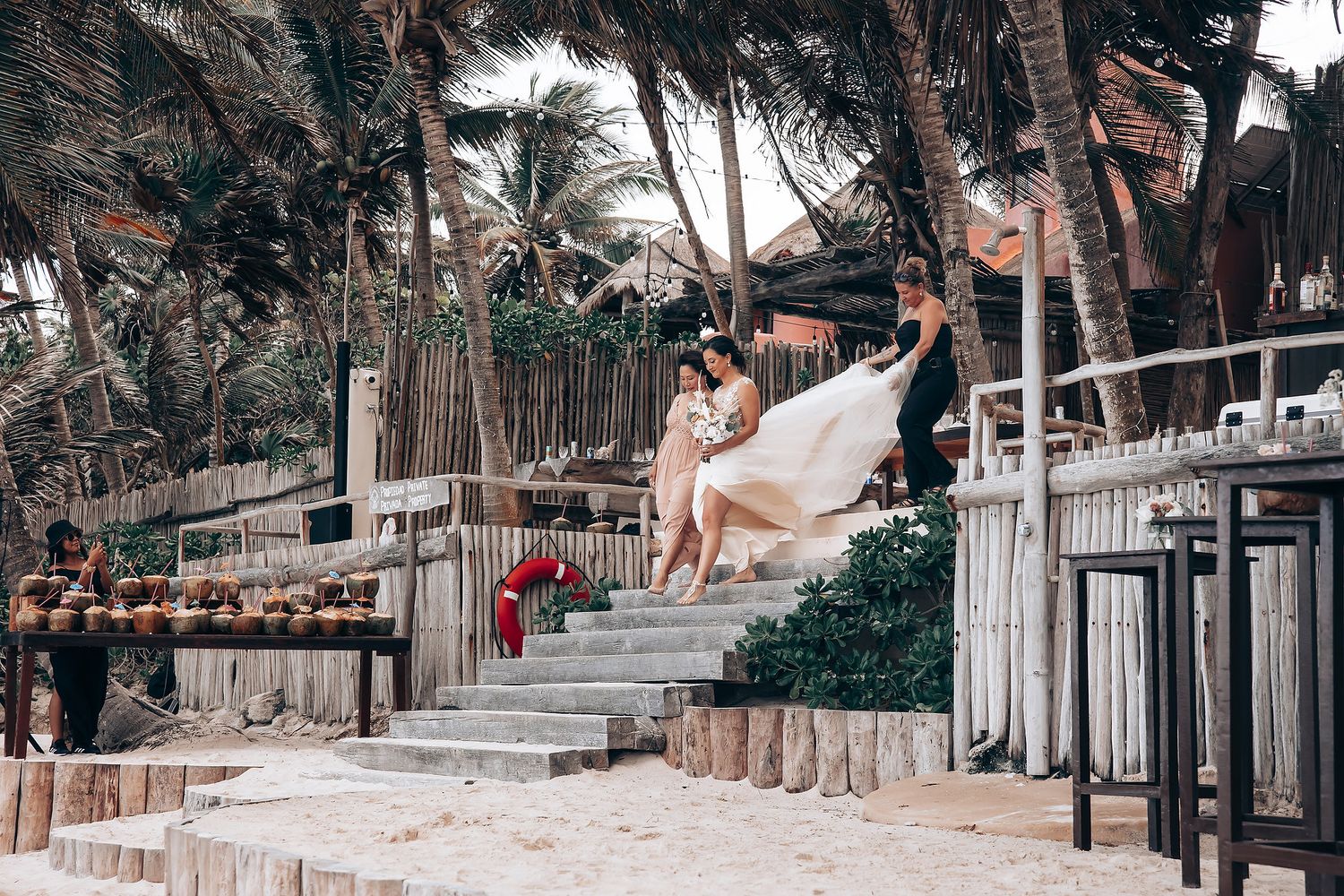 Tropical beachfront venue with wooden railings and palm trees along the shoreline.