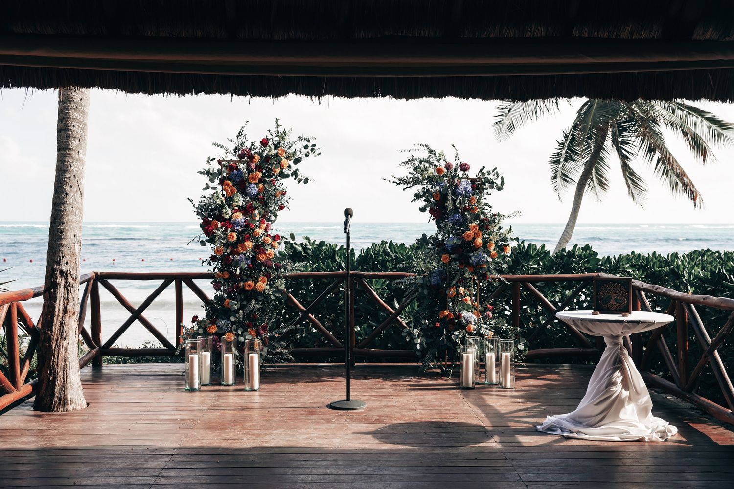 Elegant outdoor wedding ceremony setup with colorful floral arches overlooking a tropical ocean view.