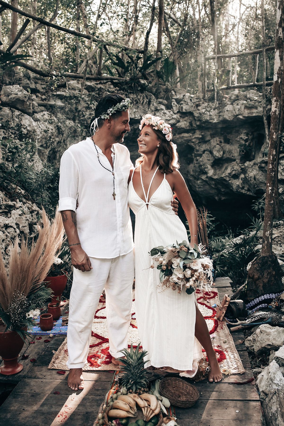 A person in traditional dress performs a ritual or ceremony in a tropical forest setting.