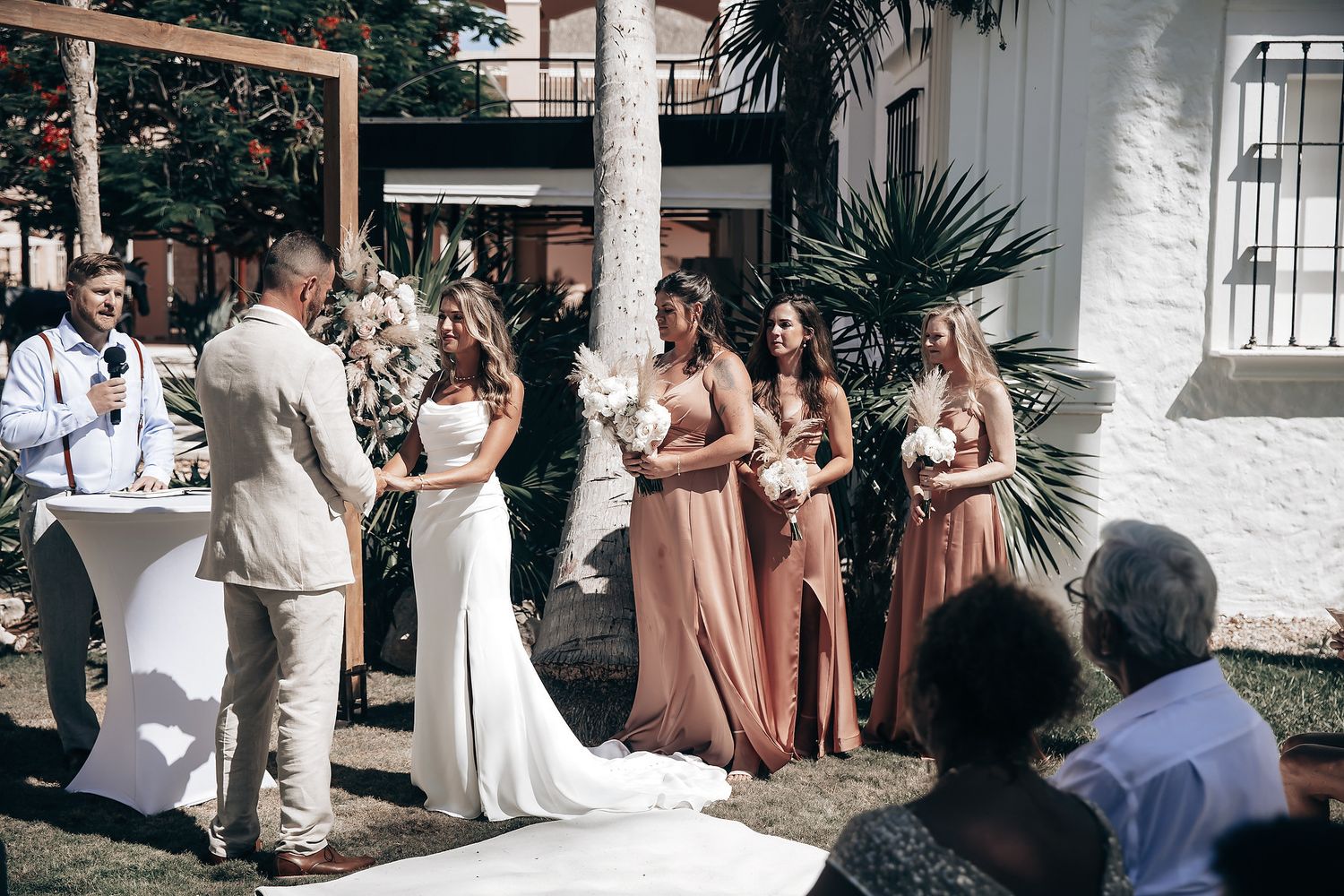 A bride and groom are exchanging vows during their outdoor wedding ceremony.