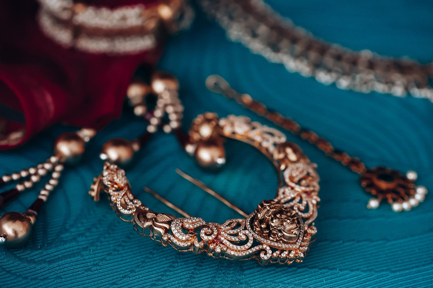Elegant gold and pearl bridal jewelry sets displayed on a turquoise blue background.