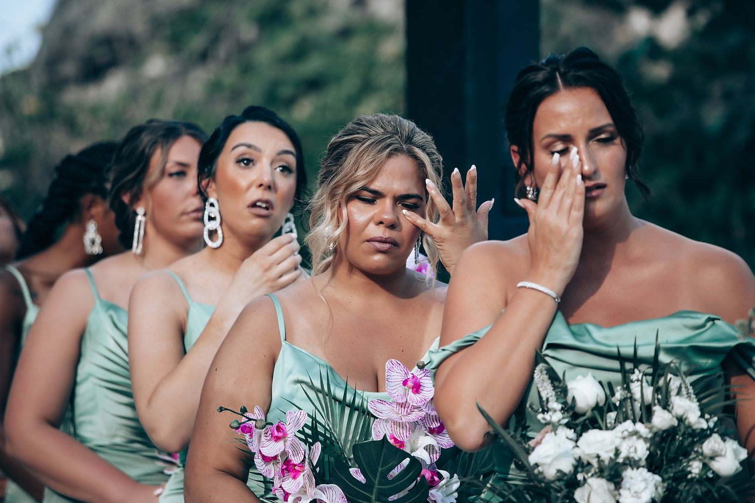 Bridesmaids in mint green dresses holding pink and white floral bouquets.