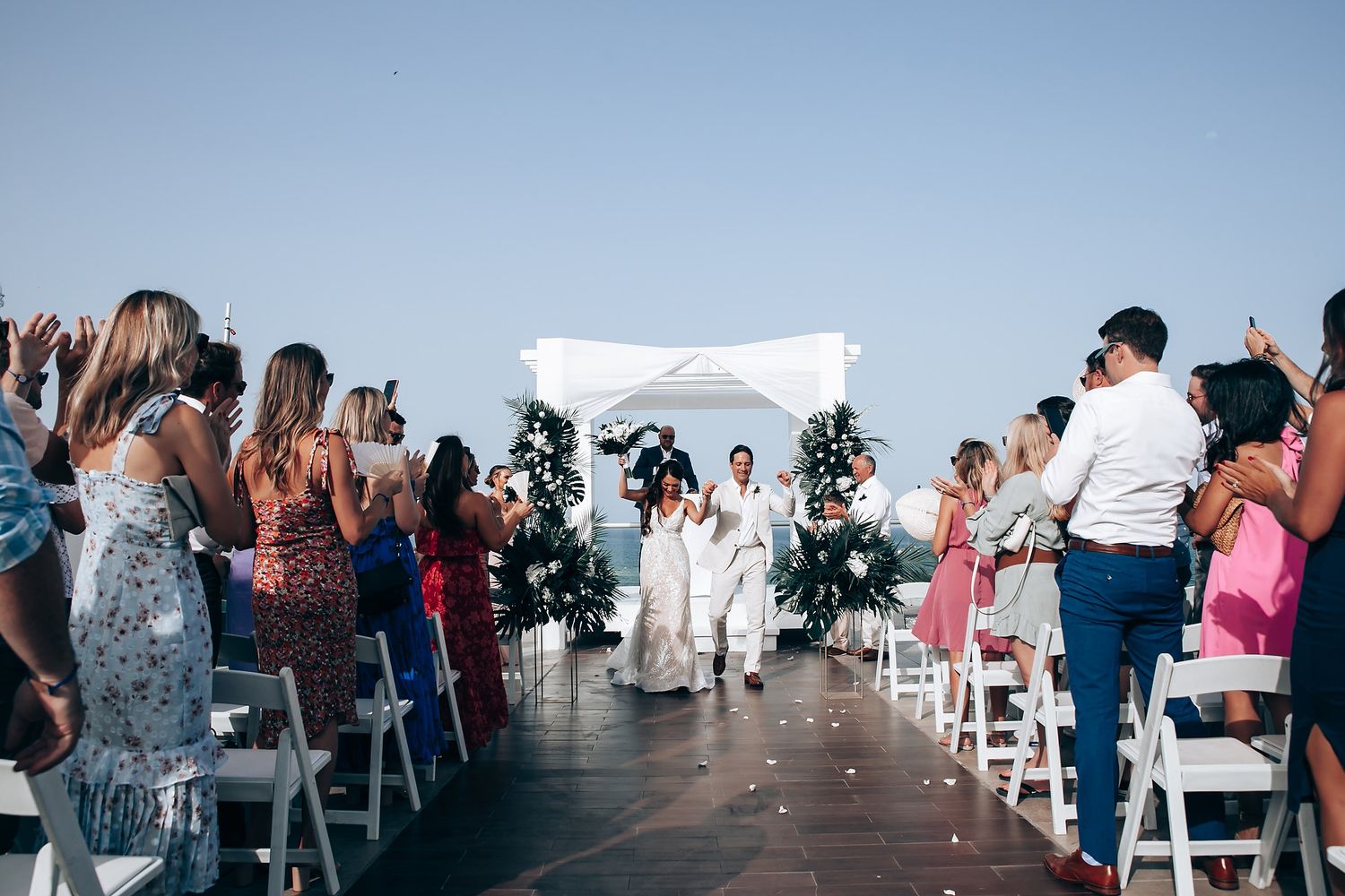 Wedding ceremony processional on rooftop venue with guests taking photos and ocean views.