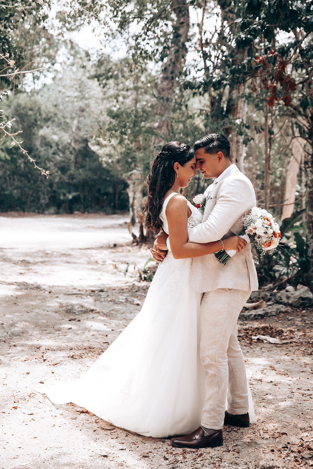 Romantic embrace between newlyweds on rustic forest path.