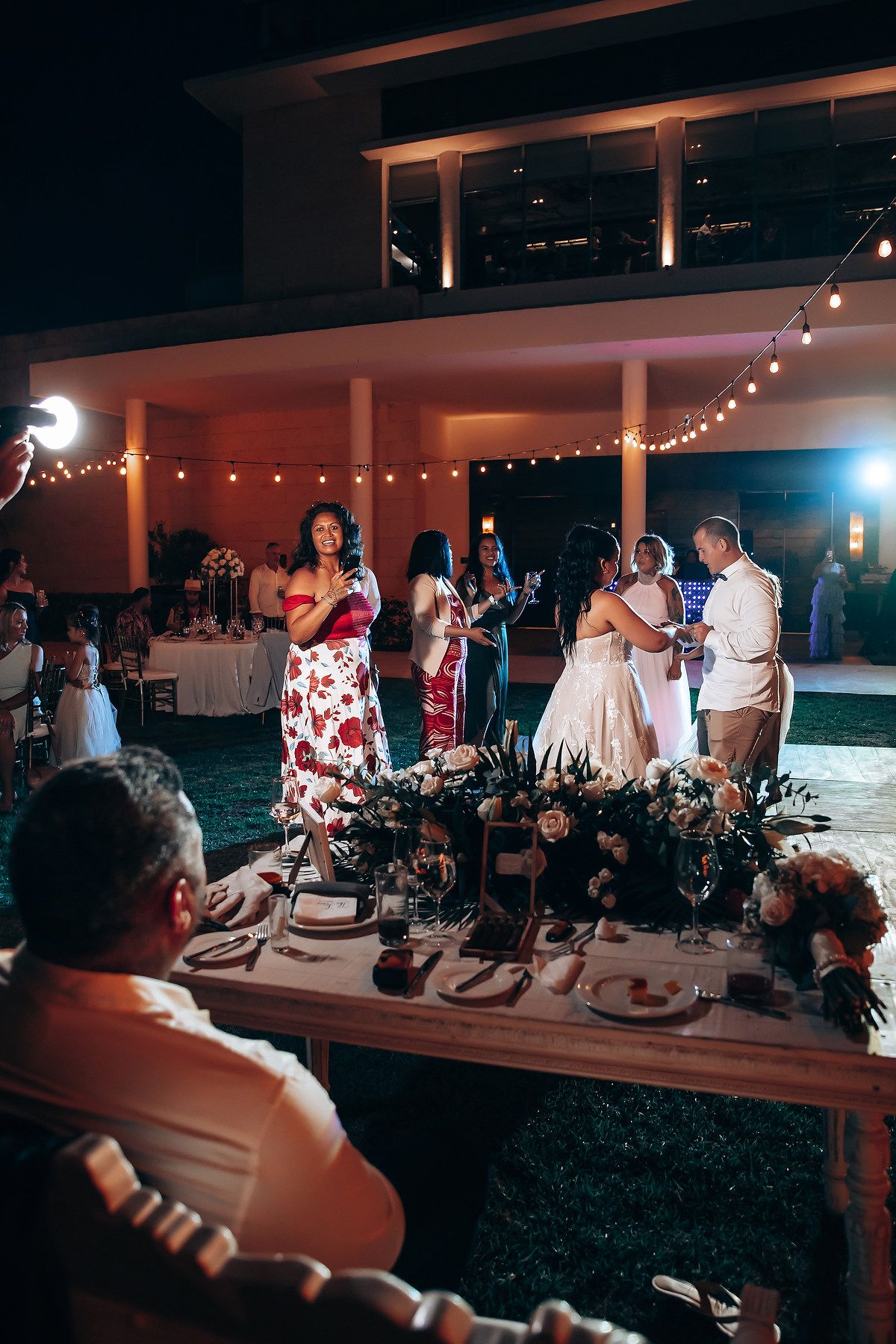 Evening wedding reception with string lights and guests gathered at the bar area.