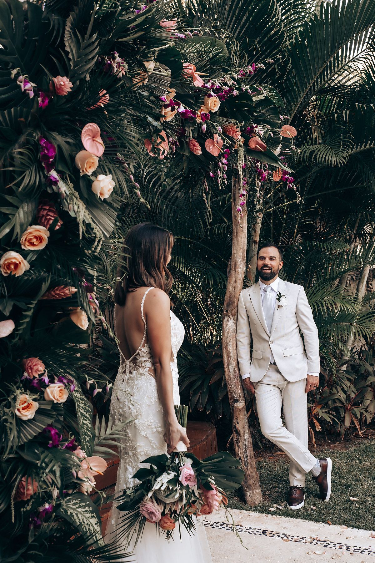 Tropical wedding ceremony setup with floral arrangements and palm trees in an outdoor garden.