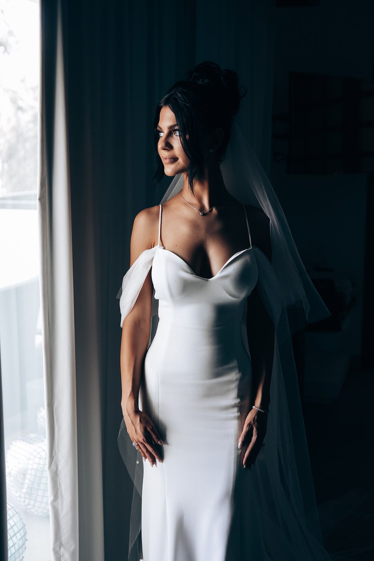 Elegant white wedding gown captured in moody, dramatic lighting.