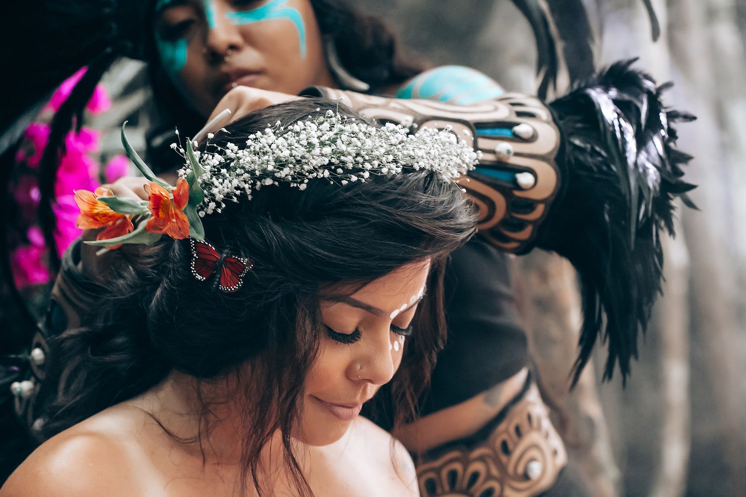 A person wearing a floral crown and dark hair looks down in a moody, artistic portrait.