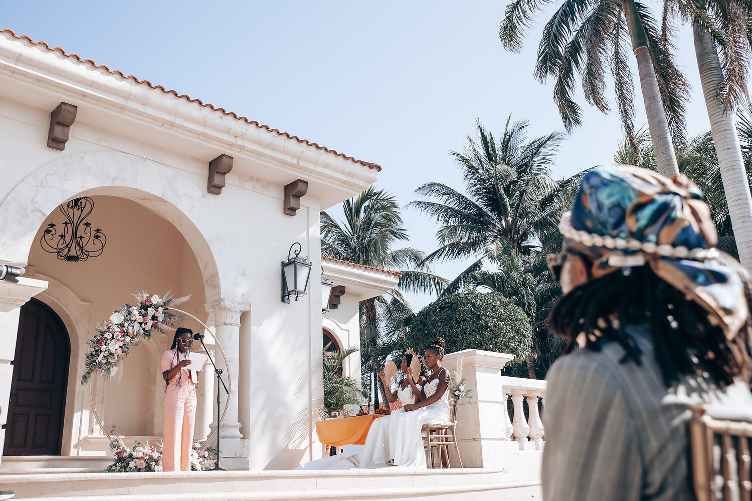 Spanish colonial style wedding venue with white arches and palm trees.